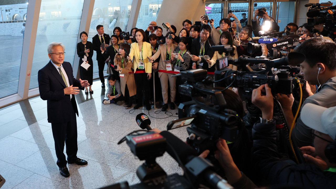 Nvidia CEO Jensen Huang answers reporters’ questions at the entrance of the Gyeongju Arts Center in North Gyeongsang Province before attending a press conference on Friday. (Im Se-jun/The Korea Herald)