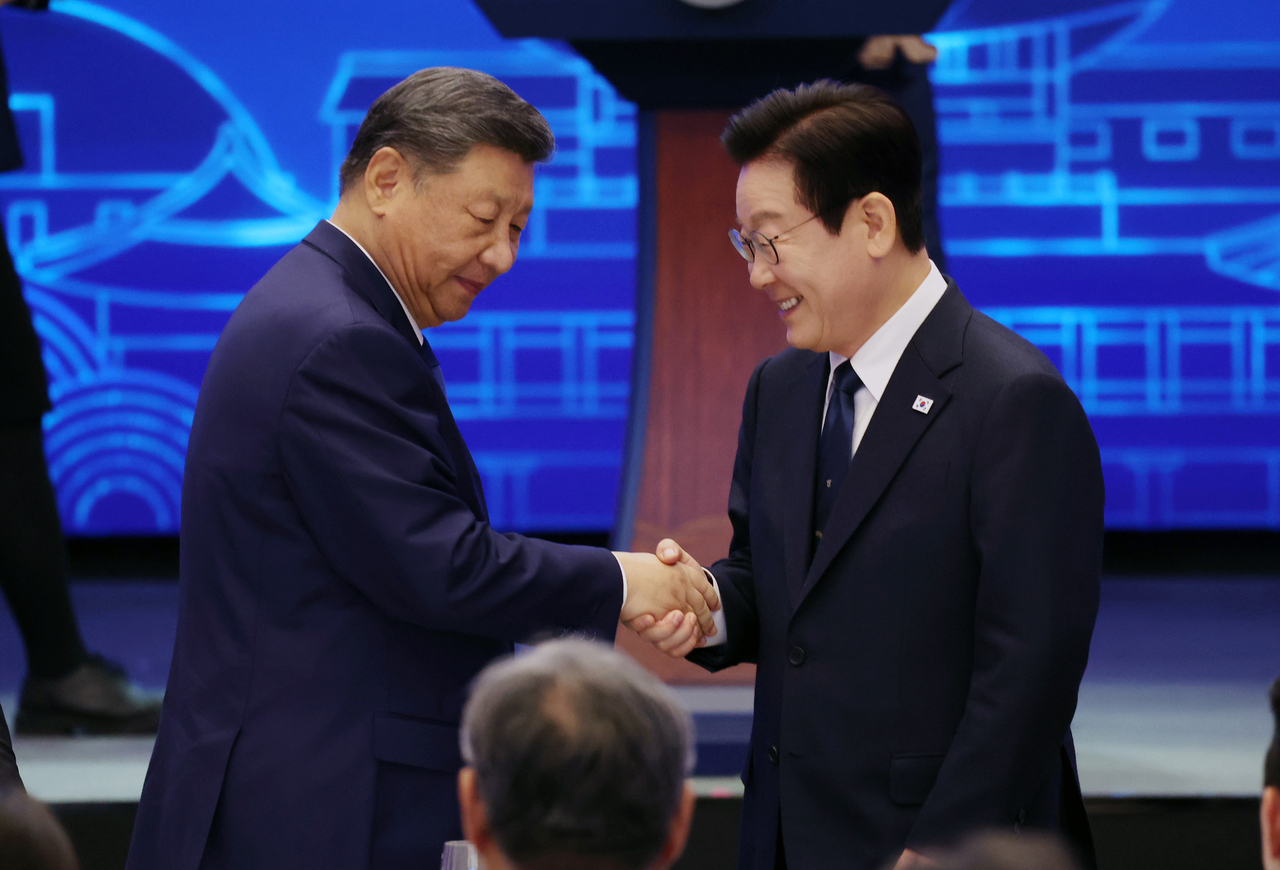 President Lee Jae Myung (right) and Chinese President Xi Jinping shake their handsduring a state banquet held at Sono Calm Gyeongju in North Gyeongsang Province on Saturday. (Yonhap)