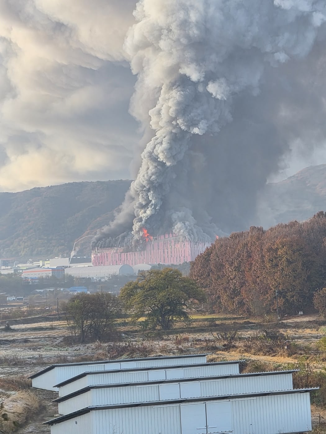 A dense column of smoke rises high above the Cheonan countryside as fire consumes the E-Land facility on Saturday. (Yonhap)