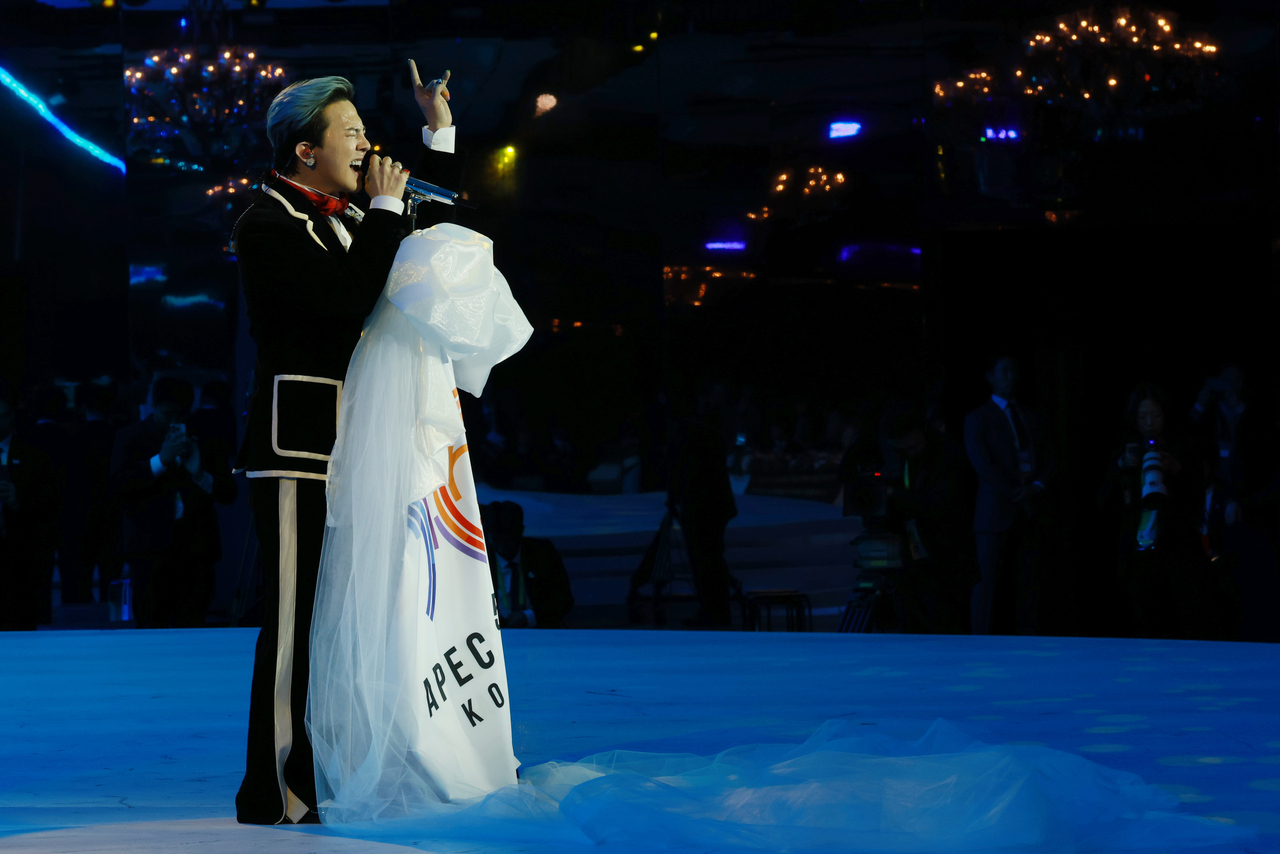 K-pop artist G-Dragon holds an APEC flag as he performs during the APEC 2025 summit gala dinner in Gyeongju, North Gyeongsang Province, Friday. (Yonhap)