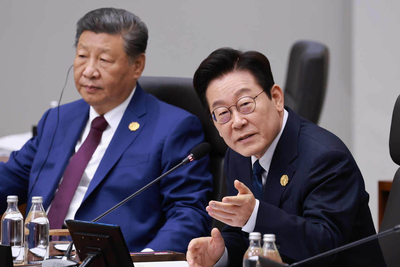South Korean President Lee Jae Myung (right) chairs an APEC Economic Leaders' Meeting session on Saturday, which was attended by China's President Xi Jinping (left). (Yonhap)