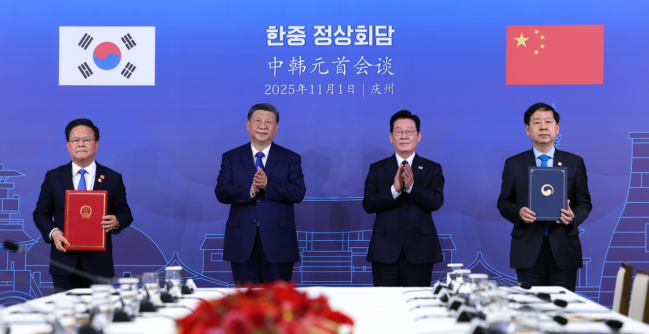 Deputy Prime Minister and Finance Minister Koo Yun-cheol and Zheng Shanjie, chairman of China’s National Development and Reform Commission, sign an agreement as President Lee Jae Myung and Chinese President Xi Jinping look on,  at the Gyeongju National Museum on Saturday. (Yonhap)